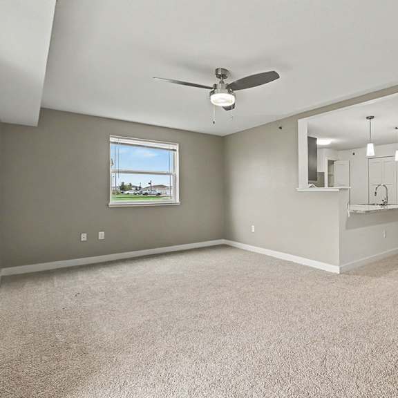 Thumbnail 6 of 12 An enlarged living room with a ceiling fan and a large window at The Reserve at The Reserve at Destination Pointe in Grimes, IA 50111