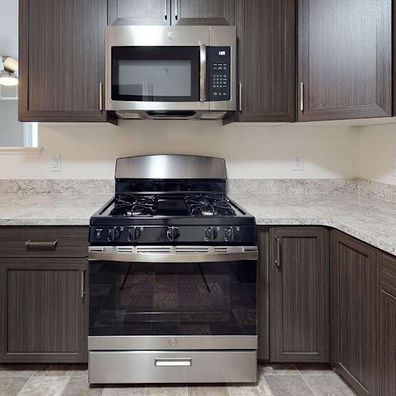 Thumbnail 5 of 9 A modern kitchen with a stainless steel stove top oven and microwave at The Reserve at Destination Pointe apartments, Grimes, IA