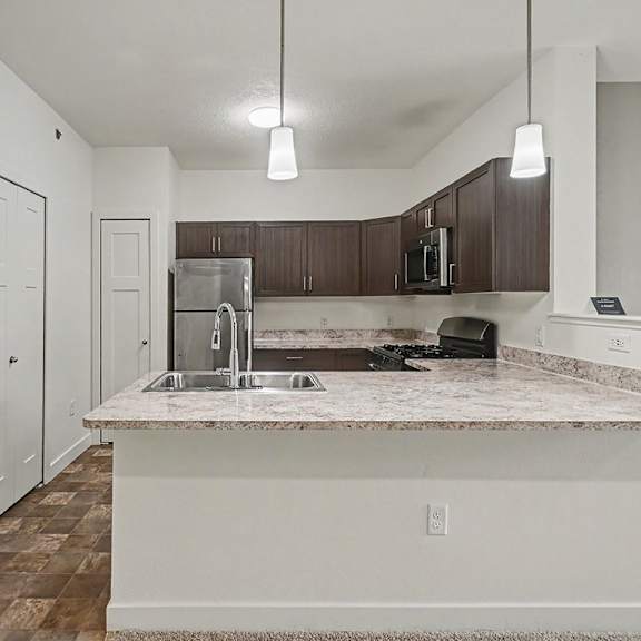 Thumbnail 8 of 16 A kitchen with a breakfast bar and stainless steel appliances at The Reserve at The Reserve at Destination Pointe in Grimes, IA 50111