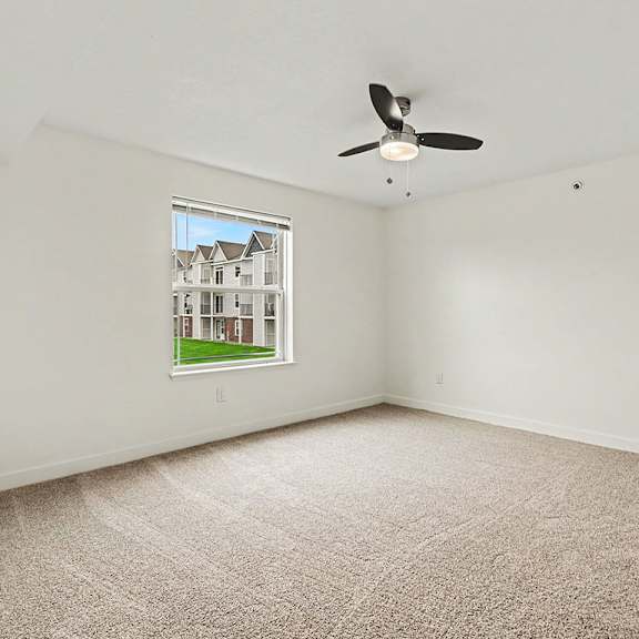 Thumbnail 14 of 16 A bedroom with a carpeted floor and a ceiling fan at The Reserve at The Reserve at Destination Pointe in Grimes, IA 50111