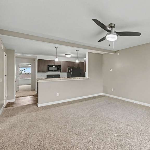 Thumbnail 6 of 16 A spacious living and dining room with a ceiling fan and carpeted floor at The Reserve at The Reserve at Destination Pointe in Grimes, IA 50111