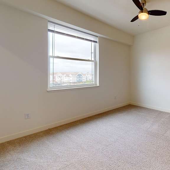Thumbnail 10 of 12 A bedroom with a ceiling fan and a window at The Reserve at Destination Pointe apartments, Grimes, IA