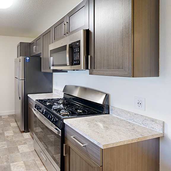 Thumbnail 5 of 12 A kitchen with a stove top oven, microwave and dishwasher at The Reserve at Destination Pointe apartments, Grimes, IA.