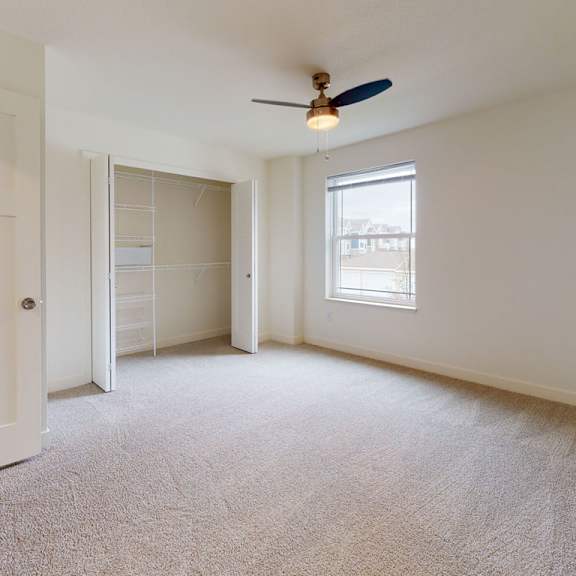 Thumbnail 9 of 9 A bedroom with a ceiling fan, window., and walk-in closet at The Reserve at Destination Pointe apartments, Grimes, IA