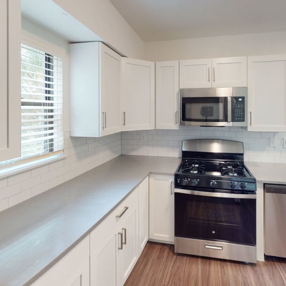 Thumbnail 7 of 10 a kitchen with white cabinets and a stove and a microwave at Green Ridge Apartments, Grand Rapids, MI, 49544