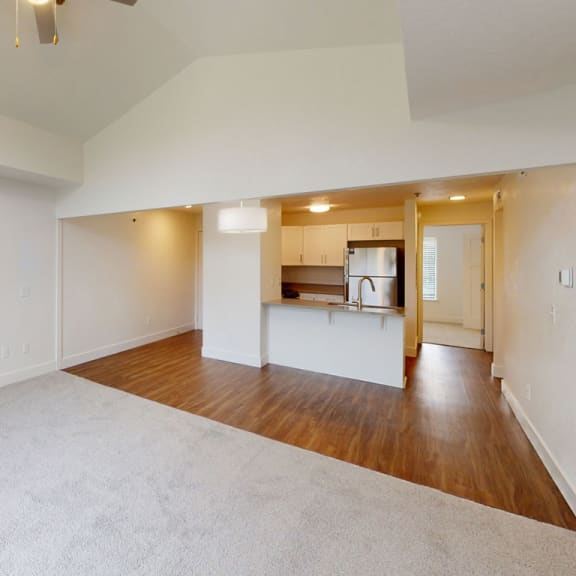 Thumbnail 5 of 14 an empty living room with a kitchen in the background at Green Ridge Apartments, Grand Rapids, Michigan