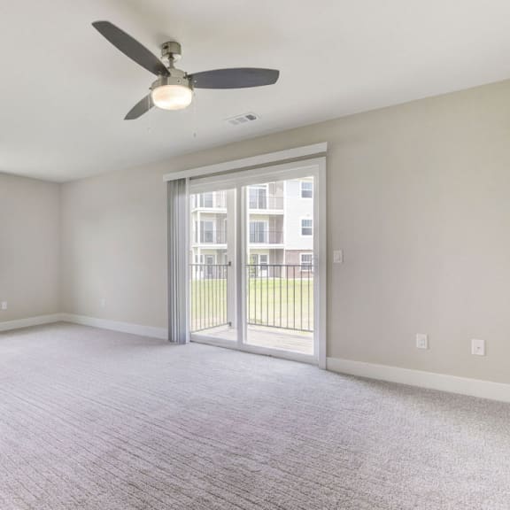 Thumbnail 3 of 12 an empty living room with a ceiling fan and a door to a balcony  at Signature Pointe Apartment Homes, Alabama, 35611
