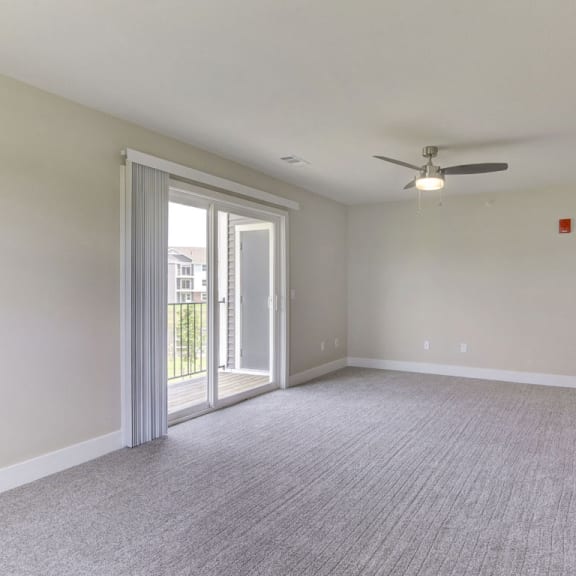 Thumbnail 4 of 12 an empty living room with a ceiling fan and a door to a balcony  at Signature Pointe Apartment Homes, Alabama
