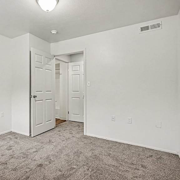 Thumbnail 22 of 24 A white room with a carpeted floor and a white closet with shelves.