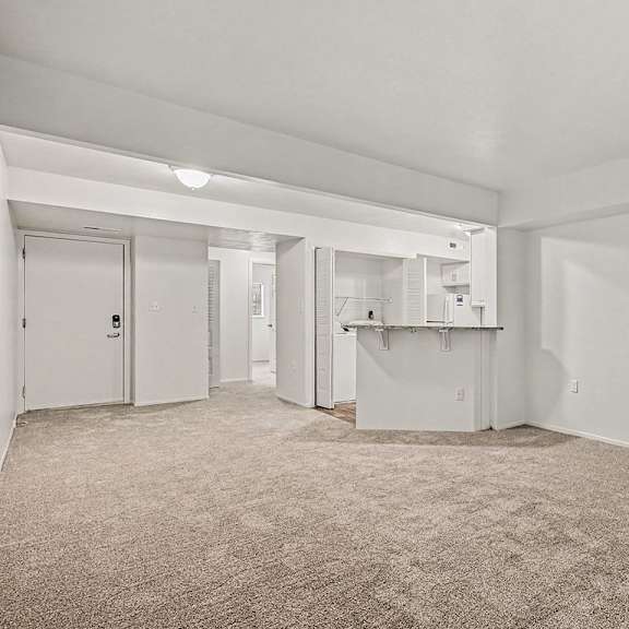 Thumbnail 8 of 24 A sparsely furnished room with a carpeted floor and white walls.