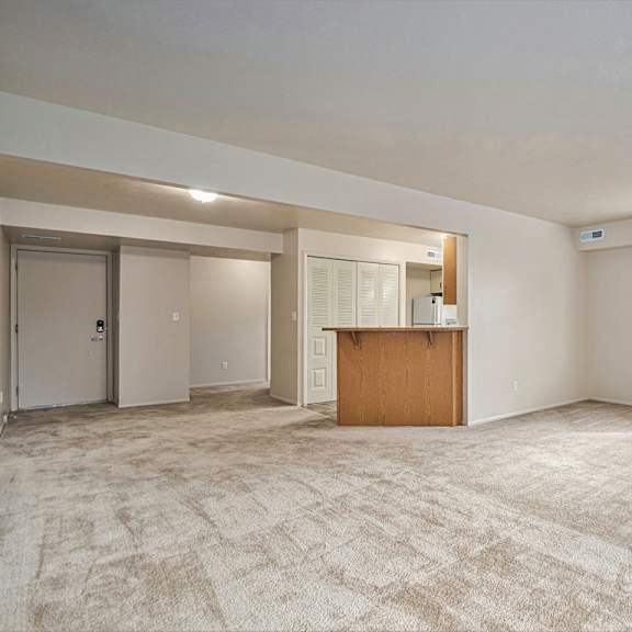 Thumbnail 7 of 24 A spacious room with a carpeted floor and a wooden cabinet in the middle.