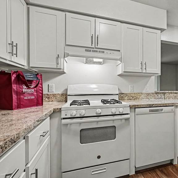 Thumbnail 11 of 24 A kitchen with a white stove and cabinets.
