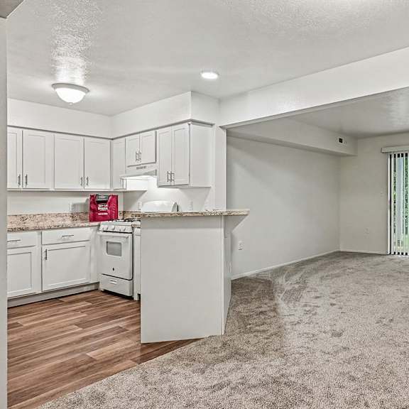 Thumbnail 3 of 24 A white kitchen with a window and a carpeted floor.