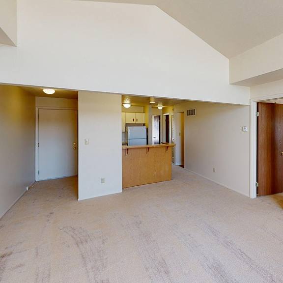 Thumbnail 5 of 8 A large living room with a cathedral ceiling and a kitchen with breakfast bar at South Bridge Apartments, Fort Wayne, Indiana
