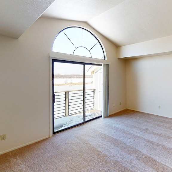 Thumbnail 4 of 8 A living room with a cathedral ceiling and a slider to a balcony at South Bridge Apartments, Fort Wayne, Indiana