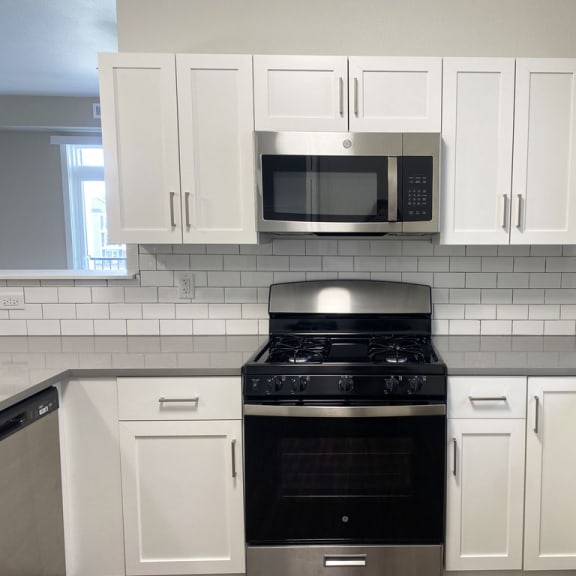 Thumbnail 7 of 10 a kitchen with white cabinets and a stainless steel stove and microwave at Stoney Pointe Apartment Homes, Wichita