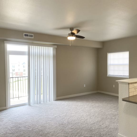 Thumbnail 5 of 10 end living room with a ceiling fan and a slider to a balcony at Stoney Pointe Apartment Homes, Wichita, KS