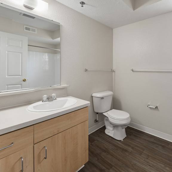 Thumbnail 10 of 13 A bathroom with a window, toilet, sink, and mirror at Stoney Pointe Apartment Homes, Kansas