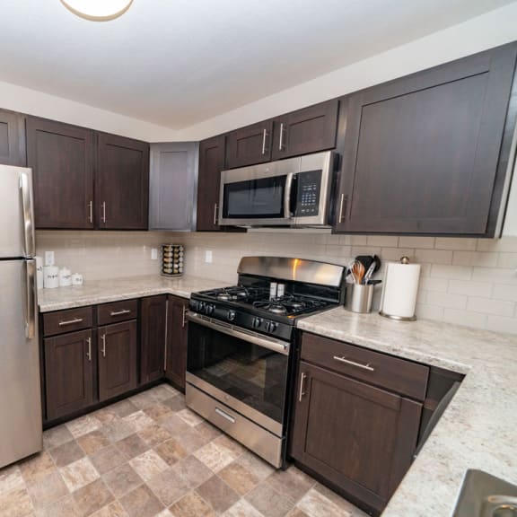 Thumbnail 6 of 10 a kitchen with stainless steel appliances and wooden cabinets at Strathmore Apartment Homes, West Des Moines