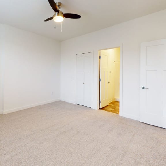 Thumbnail 13 of 14 a bedroom with white walls and a ceiling fan and a door to an ensuite at Strathmore Apartment Homes, West Des Moines, 50266