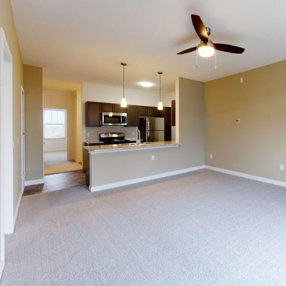 Thumbnail 7 of 14 A living and dining room with a ceiling fan and breakfast bar at Strathmore Apartment Homes, West Des Moines