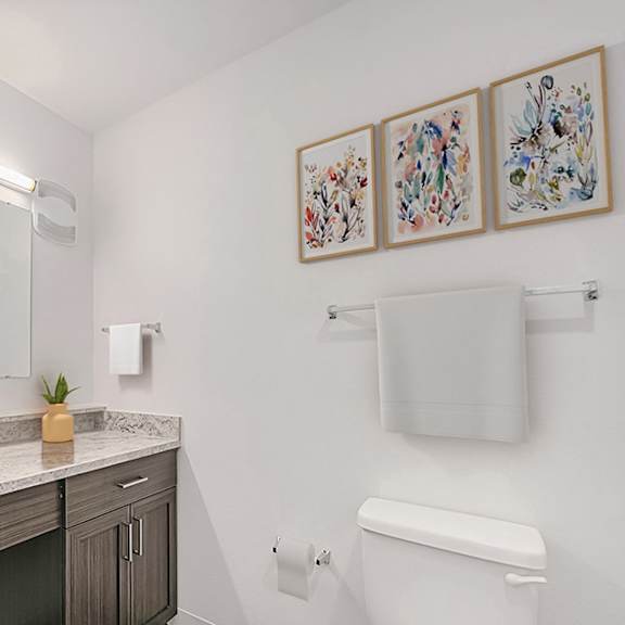 Thumbnail 8 of 9 A bathroom with a sink, toilet, and a mirror at Strathmore Apartment Homes in West Des Moines, IA