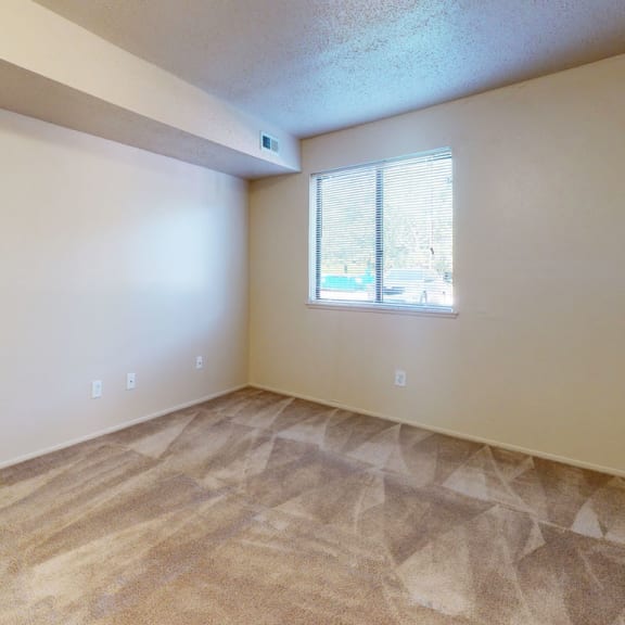 Thumbnail 8 of 9 an empty living room with a white door and a window at Swiss Valley Apartments, Wyoming, MI