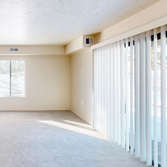 Thumbnail 4 of 7 an empty living room with sliding glass doors to a kitchen  at Swiss Valley Apartments, Michigan