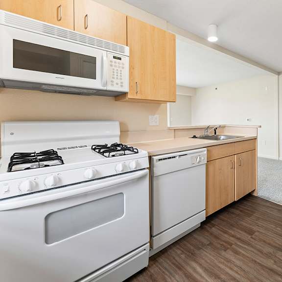 Thumbnail 7 of 15 A kitchen with a white stove and microwave above it at Tall Oaks Apartment Homes, Kalamazoo, MI