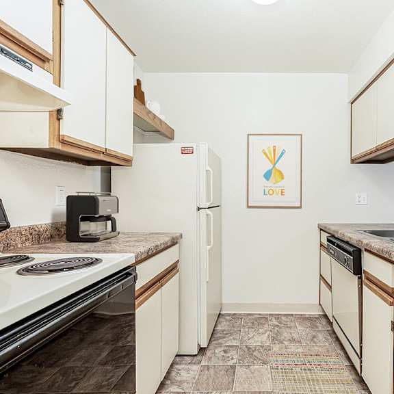 Thumbnail 11 of 19 A galley style kitchen with a dishwasher  at Tanglewood Apartments, Oak Creek, WI