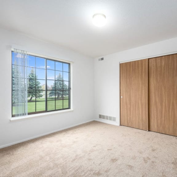 Thumbnail 19 of 20 large bedroom with a window and closet doors at Tanglewood Apartments, Oak Creek, WI, 53154