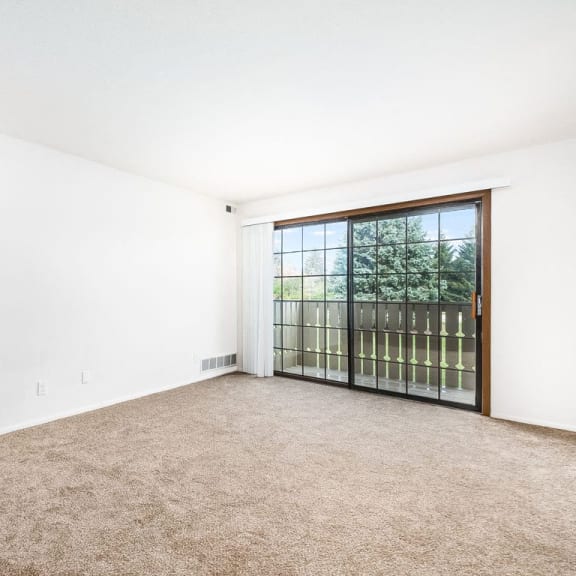 Thumbnail 6 of 20 a living room with carpeting leading to a private balcony at Tanglewood Apartments, Oak Creek, WI, 53154