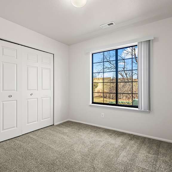Thumbnail 16 of 19 A bedroom with a large window and closet at Tanglewood Apartments, Oak Creek, WI