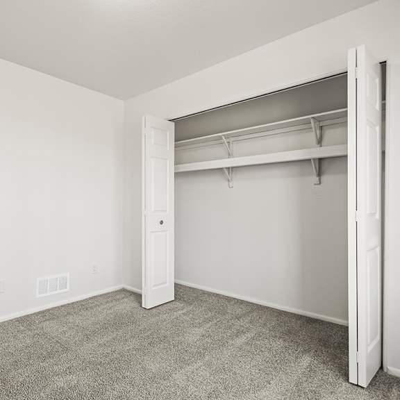 Thumbnail 17 of 19 A white bedroom with a large closet and carpeted floor at Tanglewood Apartments, Oak Creek, WI