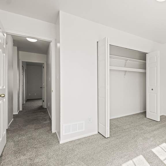 Thumbnail 19 of 19 A bedroom with a carpeted floor and a white closet at Tanglewood Apartments, Oak Creek, WI