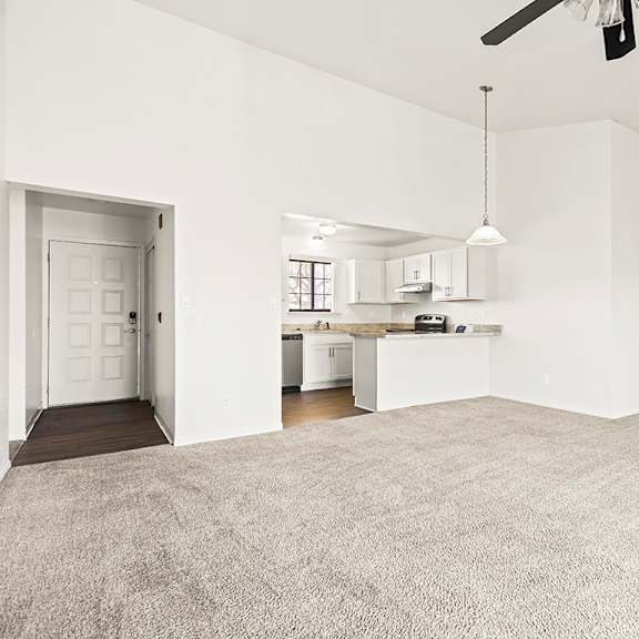 Thumbnail 4 of 19 A large, empty living and dining room with a ceiling fan and a kitchen area in the background at Tanglewood Apartments, Oak Creek, WI