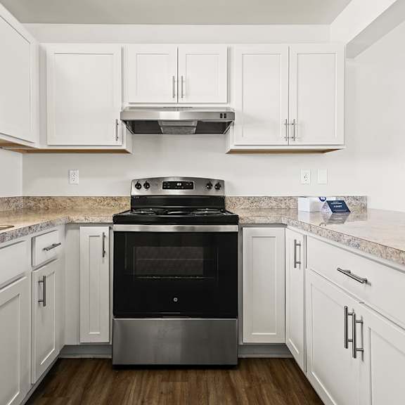 Thumbnail 7 of 19 A modern kitchen with white cabinets and a stainless steel oven at Tanglewood Apartments, Oak Creek, WI