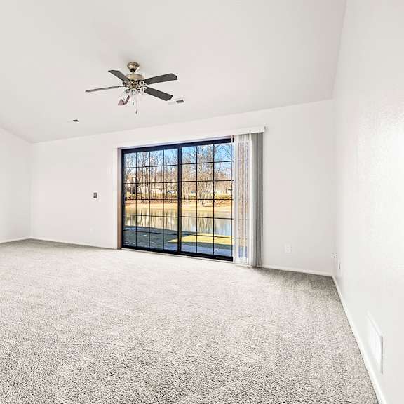 Thumbnail 3 of 19 A spacious living room with a ceiling fan and a sliding glass door leading to a patio at Tanglewood Apartments, Oak Creek, WI