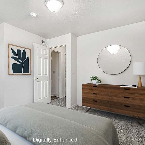 Thumbnail 9 of 13 A bedroom with a bed, dresser, and mirror at The Highlands Apartments, Elkhart