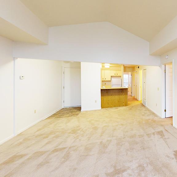 Thumbnail 4 of 10 A spacious living room with a cathedral ceiling and plush carpet at Tracy Creek Apartment Homes in Perrysburg, OH