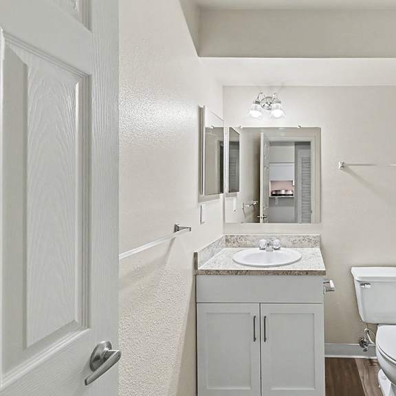 Thumbnail 9 of 11 A white bathroom with a toilet, sink, and bathtub at Trappers Cove Apartments, Lansing