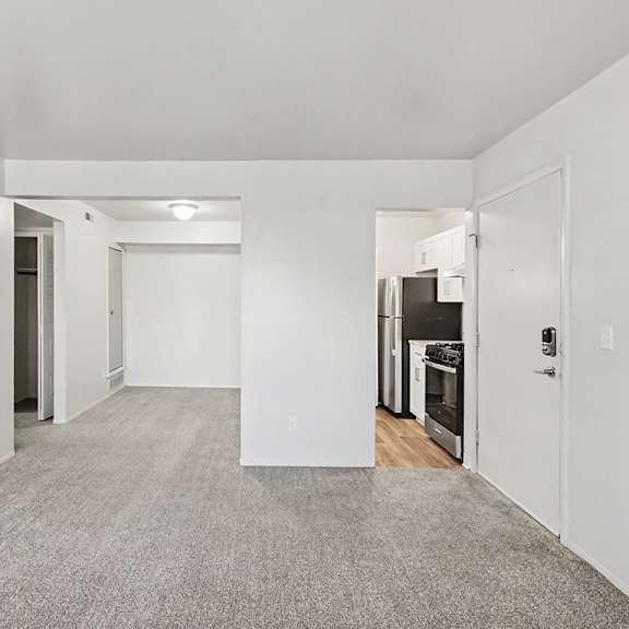 Thumbnail 5 of 11 A spacious living and dining room with a carpeted floor and white walls at Trappers Cove Apartments, Lansing