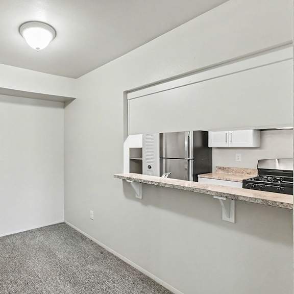Thumbnail 6 of 11 A dining room with a grey carpet and a breakfast bar at Trappers Cove Apartments, Lansing