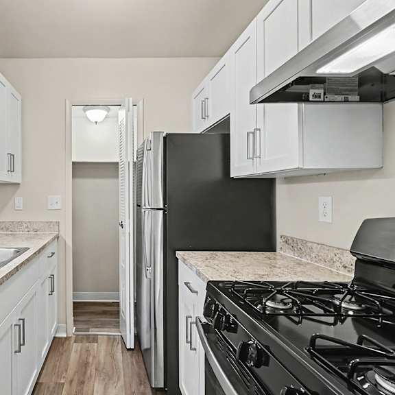 Thumbnail 7 of 11 A kitchen with stainless steel appliances, a pantry and white appliances at Trappers Cove Apartments, Lansing