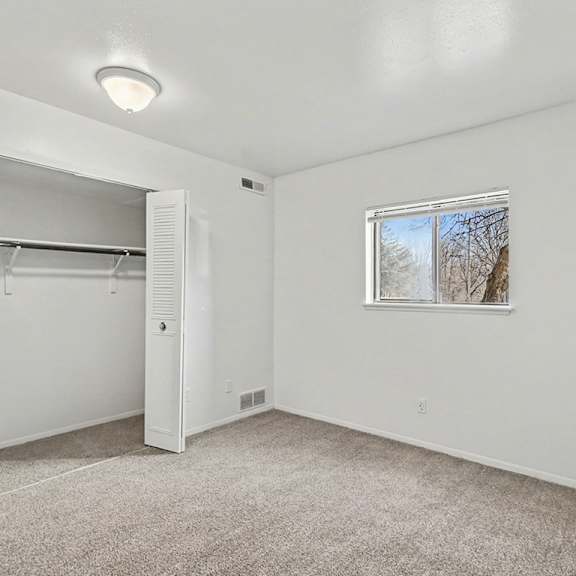 Thumbnail 11 of 11 A white bedroom with a window and a large closet at Trappers Cove Apartments, Lansing