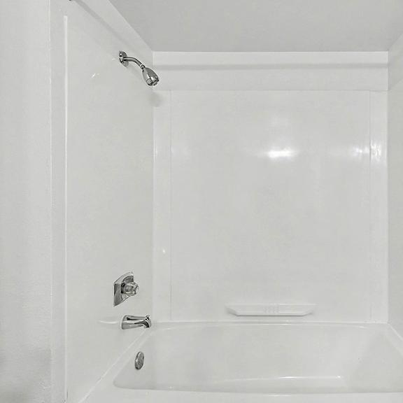 Thumbnail 9 of 12 A white bathroom with a tub and toilet at Trappers Cove Apartments, Lansing