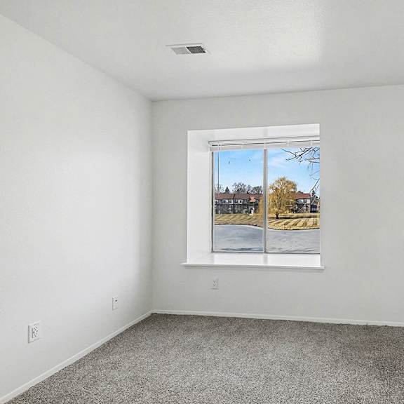 Thumbnail 11 of 12 A bedroom with a large window showing a pond view at Trappers Cove Apartments, Lansing