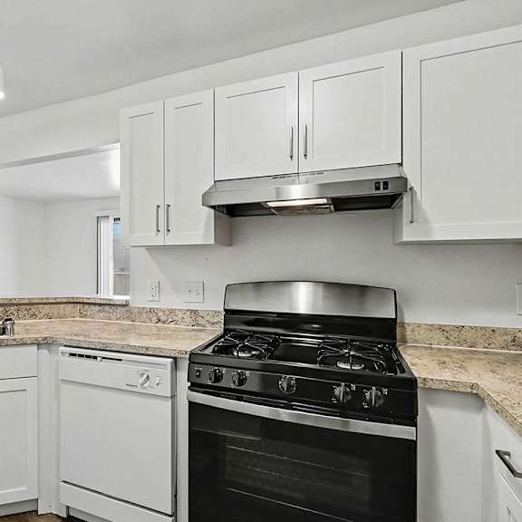 Thumbnail 5 of 12 A kitchen with a stainless steel gas stove, dishwasher, a white cabinets at Trappers Cove Apartments, Lansing