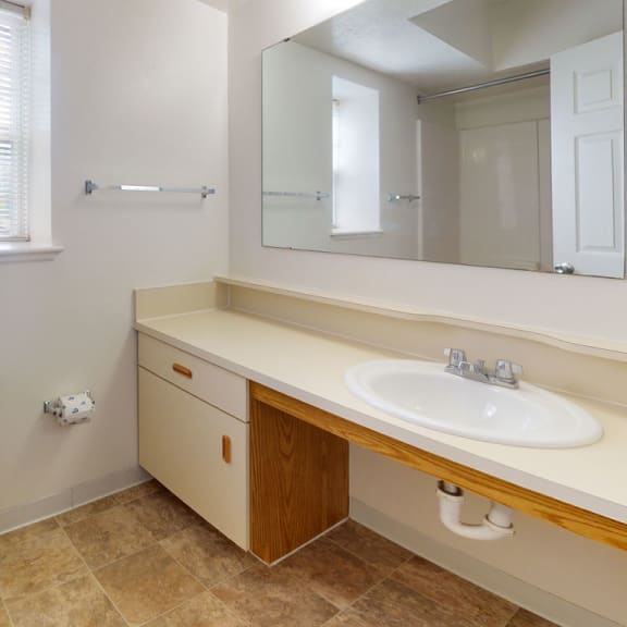 Thumbnail 4 of 7 a bathroom with a toilet and a sink and a mirror at Trillium Pointe Apartment Homes, Jackson, MI, 49201