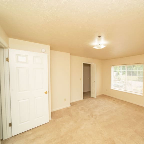 Thumbnail 8 of 12 an empty living room with a white door and a window at Trillium Pointe Apartment Homes, Jackson, Michigan
